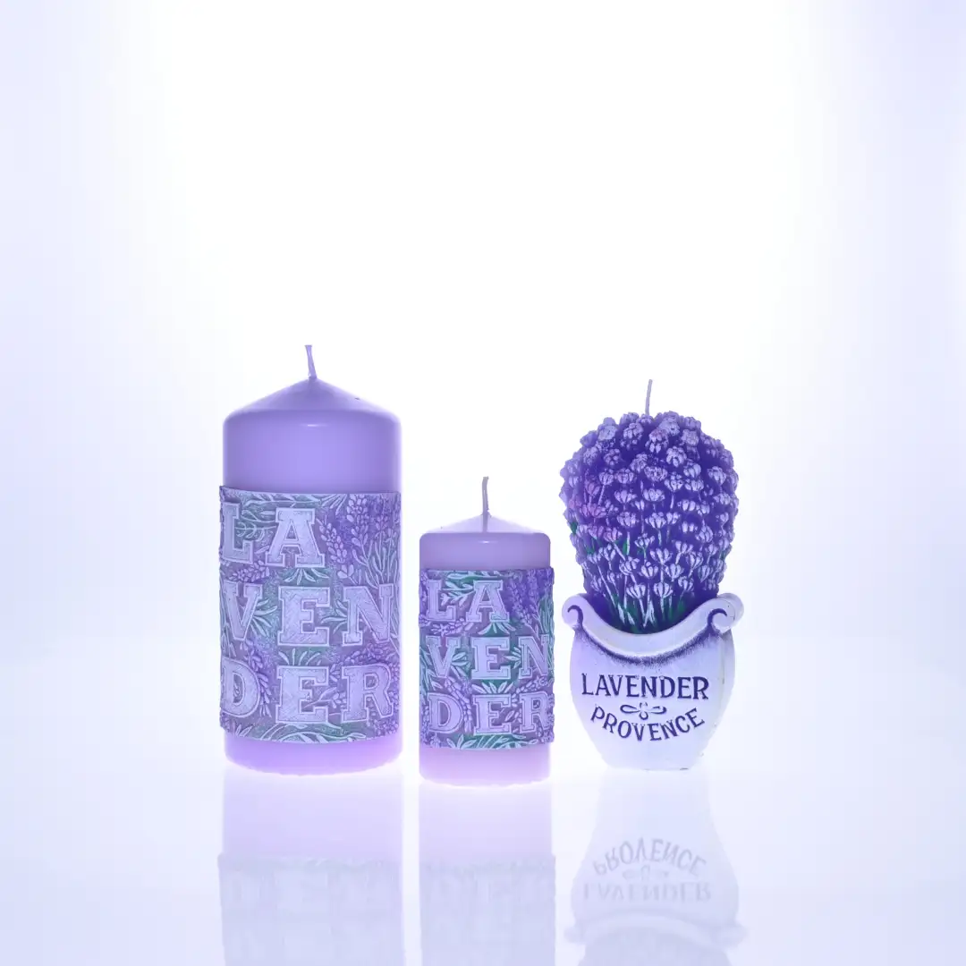 Zestaw trzech lawendowych świec w odcieniach fioletu – dwie cylindryczne z wypukłym napisem „LAVENDER” oraz jedna w kształcie bukietu lawendy w ozdobnej doniczce. Ustawione na białym tle. Idealne jako dekoracje do wnętrz i ozdoba na prezent.